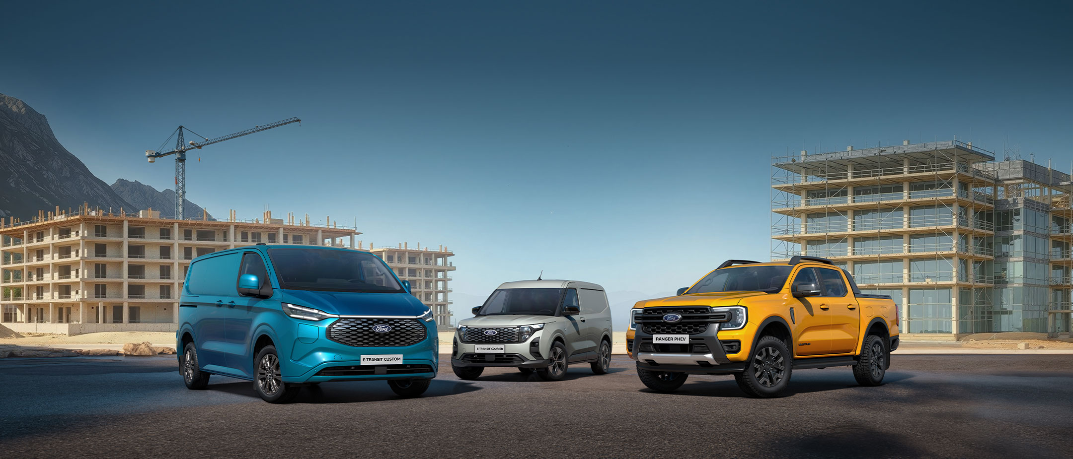 Ein Ford E-Transit Custom, ein Ford E-Transit Courier und ein Ford Ranger PHEV stehend auf einer Strasse. Ein Ford E-Transit Custom, ein Ford E-Transit Courier und ein Ford Ranger PHEV stehend auf einer Strasse.