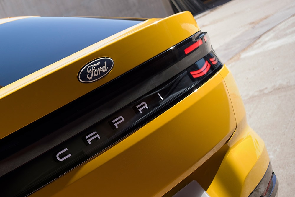 Eine Nahansicht des «Capri»-Schriftzugs an der Rückseite eines gelben neuen vollelektrischen Ford Capri® SUV. 